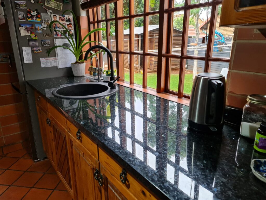 This beautiful unique granite has green flakes that shine in it. It works well with these lovely wooden cupboards.